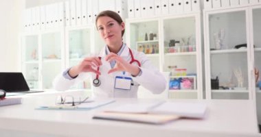 Beyaz üniformalı kadın doktor, yürekten bir sevgi belirtisi ya da jesti gösteriyor. Cerrah, hastaların hastaneye kaldırılması gerektiğini gösteriyor.
