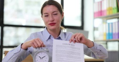 İş kadını kontrat ve çalar saat tutuyor. İş sözleşmeleri imzalamak ve sonuçlandırmak