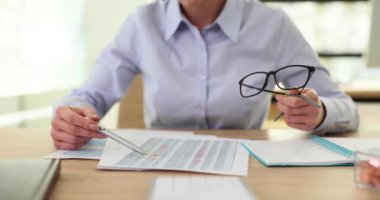 İş kadını rapor okuyor, elinde kalem ve gözlük tutuyor. İyi bir sözleşme yönetimiyle beyan