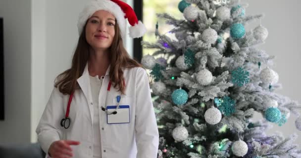 Szczęśliwa Kobieta Lekarz Białym Płaszczu Kapelusz Świętego Mikołaja Tle Choinki — Wideo stockowe
