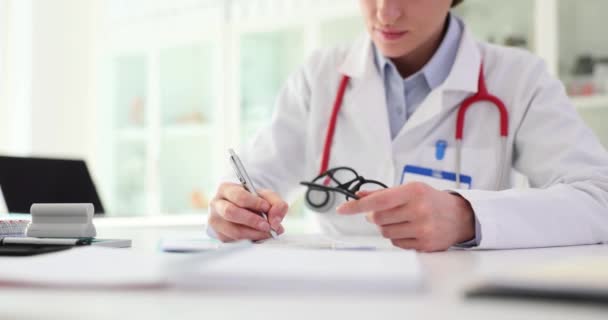 Doctora Sienta Mesa Toma Notas Libro Mayor Papel Prescribe Tratamiento — Vídeos de Stock