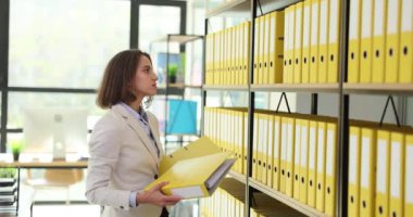 İş kadını ofisteki raflara klasör koyar. İş arşivi belgeleriyle çalışmak