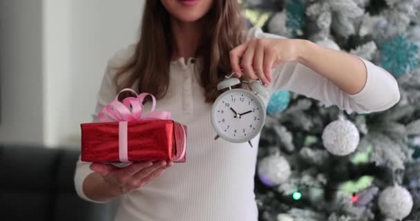 快乐的女人手里拿着闹钟和节日礼品盒 买礼物的时间到了 — 图库视频影像