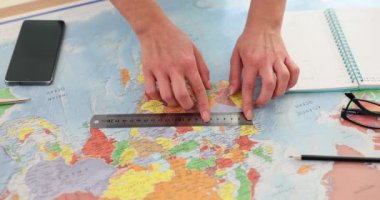 Dünya haritasında cetvel ve akıllı telefonu olan bir turist. Kadın haritacı haritadaki parametreleri ölçer