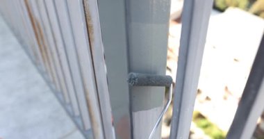 Boyacı metal korkulukları tekerlekle griye boyuyor. Boya, metal boruları paslanma ve aşınmadan korur.