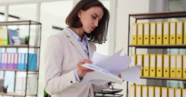 Ofiste duran kağıt muhasebe belgeleri üzerinde çalışan güzel bir kadın. İş belgeleri inceleniyor