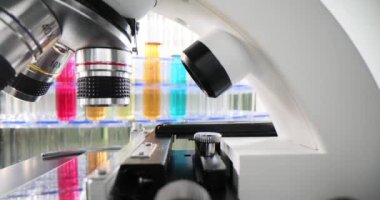 Kimya laboratuvarında raflar dolusu renkli sıvılar ve bir sıra mikroskop ile. Zehirli sıvı çözücülerinin laboratuvar araştırması.