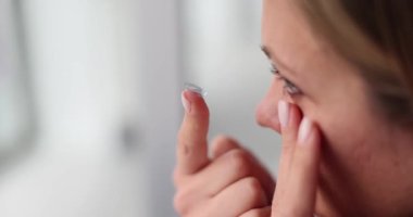 Kadın gözlere parmakla lens takıyor. Miyop ve görme gelişimi ve reklamcılık için optikler