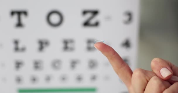 Human Finger Holds Soft Contact Lens Background Ophthalmic Chart Vision — Stock Video