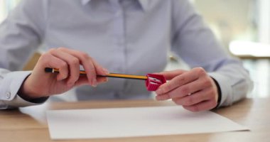 Kadın ofis çalışanı, işyerindeki masada boş bir kağıt parçasıyla kalemleri sivrileştiriyor. Meslek çizim becerisi gerektirir. Uzman iş akışı