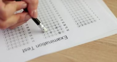 Bayan öğrenci sınav kağıdındaki yanlış cevabı kalemin ucundaki silgiyle siliyor. Bilgiyi test etmek ve konsepti test etmek