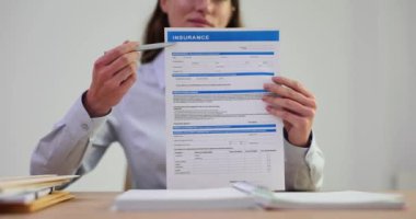 Kadın ofis çalışanı, belgenin önemini açıklarken sigorta formu doldurmaya dikkat çekiyor. Hayat kurtarmak için veri dolduruluyor