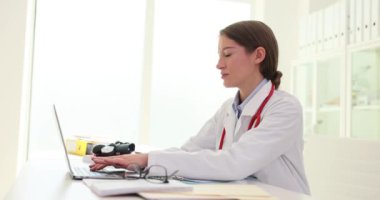 Ofisteki masada oturan hasta hastalıklarının verilerini konsantre kadın doktor yazıyor. İşe karşı sorumlu tutum ve masaları doldurma