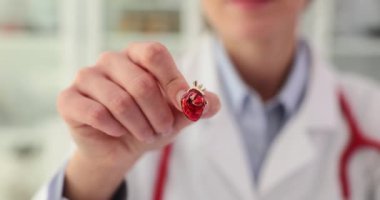 İş üniformalı kadın doktor klinikte küçük bir yapay kalp modelini elinde tutuyor. Rozet gibi yavaş çekimde insan organı