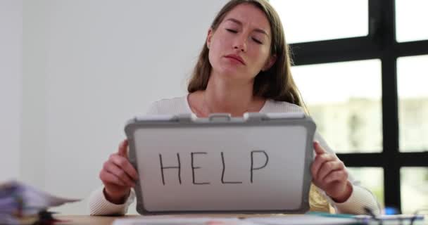 サレン女性は 救済のための嘆願のサインとしてポータブルホワイトボードに書かれた単語ヘルプを示しています 未愛の仕事とボスのスローモーションからタスクを完了することに苦しむ — ストック動画