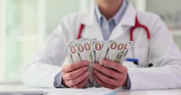 成功した女性医師は 病院で病気の患者を治療することから得られたドル紙幣を数えています スペシャリストオフィスの国際通貨の医師のための給料 キャッシュセーブメント — ストック動画