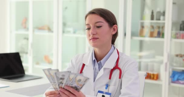 身着医疗制服的女士闻到诊所工作场所收钱的味道 从薪水中获得积极的感觉 从从事心爱的工作中获得快乐 — 图库视频影像