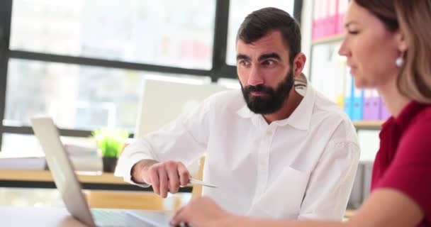 女人在笔记本电脑上向留胡子的男性员工解释公司项目的原则 办公室工作场所专家的团队合作进程缓慢 — 图库视频影像