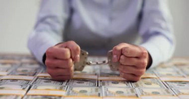 Elleri kelepçeli yozlaşmış bir politikacının elleri ve Amerikan doları. Dolandırıcılık ve yolsuzluk