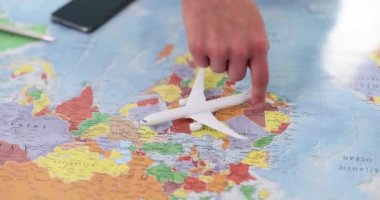 İnsan eli, dünya haritası ile uçağı tutar ve döndürür. Turizm seyahati ve hava seyahati