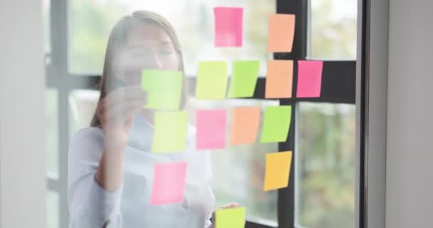 Красивая Женщина Менеджер Приклеивает Цветные Бумажки Прозрачной Стеклянной Стене Офисе — стоковое видео