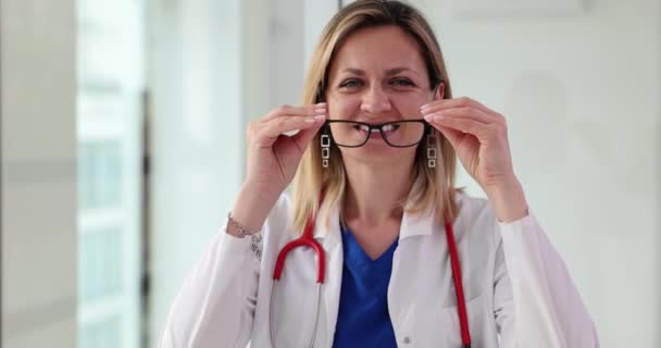 Χαμογελαστή Νεαρή Γιατρός Που Βάζει Γυαλιά Στην Κλινική Παροχή Συμβουλών — Αρχείο Βίντεο