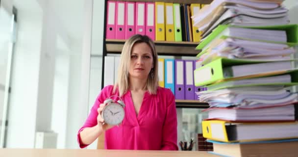 在办公室工作的女商人展示了一个闹钟 上面有一堆文件夹 严格的Seo老板 截止日期和时间管理 — 图库视频影像