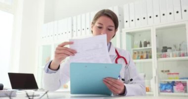 Kadın doktor, işyerindeki klinikte belge okuyor. Tıbbi teşhis ve tedavi listesi