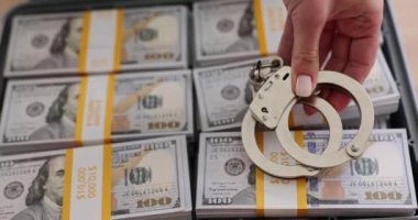 Kelepçe ve kenevir yaprakları her ihtimale karşı 100 dolarlık banknotların arka planında. Uyuşturucu kontrol memurları uyuşturucu satıcılarını gözaltına aldı