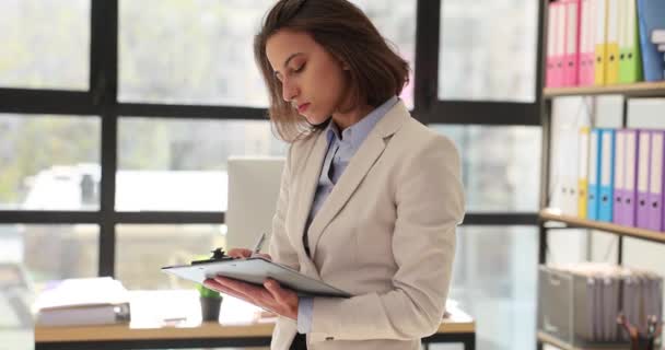 オフィスの女性マネージャーは文書を読み ノートを書く オフィスに立っている女性マーケティング担当者レポート — ストック動画
