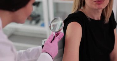 Dermatolog, klinikte büyüteç kullanarak hasta benini inceliyor. Yakın plan. Hastanede hastaların cildini muayene eden doktor.