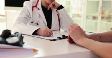 Kadın doktor hasta muayene formu dolduruyor. Profesyonel doktor klinik ziyareti sırasında kadınlara bilgi yazar ve kontrol eder.