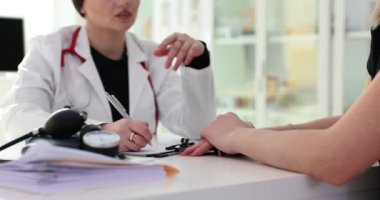 Kadın doktor hasta elini tutuyor, teselli ediyor ve sağlık hizmetlerine sempati duyuyor. Klinikteki hastalara psikolojik destek
