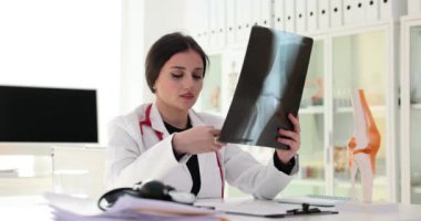 Diz röntgeni olan doktor ultrasonda dizindeki yarayı analiz ediyor. Röntgen cihazıyla hastanede çalışan bir tıp çalışanı.