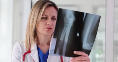 Pratisyen hekim, saydamlık tutan hasta kol kemiklerinin röntgenlerini görüyor. Travmatolog, tıbbi x-ray muayenesinin sonuçlarını inceliyor.