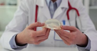 Klinikte silikonlu göğüs implantı tutan doktor plastik cerrah. Yakın çekim 4K film ağır çekim. Güzellik endüstrisi göğüs düzeltme konsepti