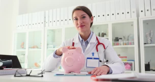 Ärztin Streichelt Sparschwein Klinik Film Zeitlupe Medizinische Spenden Und Finanzierungskonzept — Stockvideo