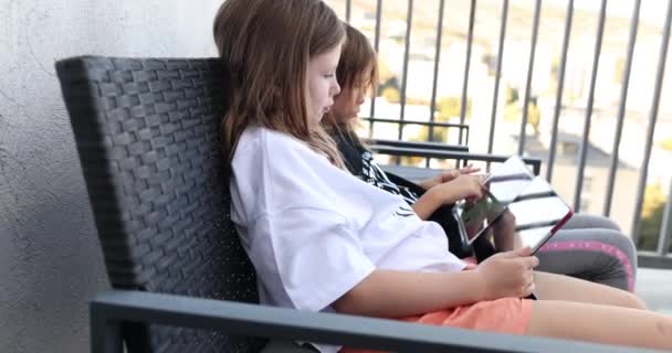 Gyerekek Kislányok Ülnek Teraszon Széken Digitális Tablettákkal Kezükben Film Lassított — Stock videók