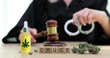 Marihuananın arka planında tahta küplere kelime ilaçları ve tokmağı yakın çekimde 4K yavaş çekimle yargılamak. Yasal ve yasadışı esrar kavramı