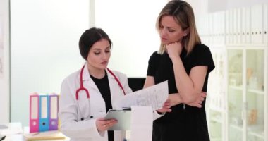 Doctor showing medical examination results to female patient in clinic 4k movie slow motion. Professional medical consultation concept