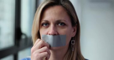 Woman victim of abuse tearing gray tape from mouth 4k movie slow motion. Freedom of speech concept