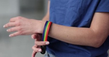 Woman hand putting on bracelet with lgbt emblem closeup 4k movie slow motion. Gay rights concept