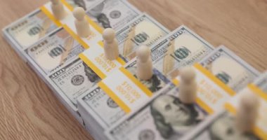 Lot of wooden people on piles of money dollars in ascending order closeup 4k movie slow motion. Salary growth in business concept