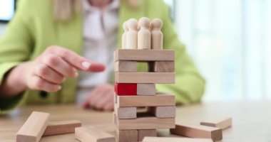 Hand taking out red wooden block from tower with crowd closeup 4k movie slow motion. Plan and strategy in business concept