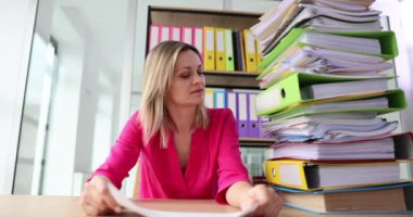 Tired businesswoman looking at stack of folders and documents and showing sign help 4k movie slow motion. Difficult work concept