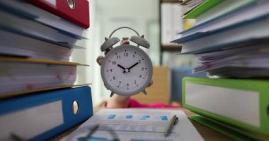 Manager hand holding alarm clock between folders with documents closeup 4k movie slow motion. Annual financial report concept