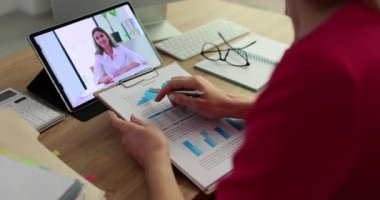 Businesswoman with documents communicating with colleague online via video link using digital tablet closeup 4k movie. Remote work with partners concept