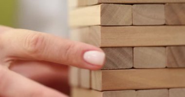 Hand taking out wooden block from structure closeup 4k movie slow motion. Insurance in business concept
