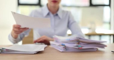 Yönetici, ofis masasında dokümanların olduğu iş dosyalarını istifliyor. Belgelerle çalış
