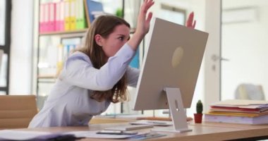 Sinirli iş kadını bilgisayar ekranını kırmaya çalışıyor. Bilgisayar arızası ya da kötü online haberler